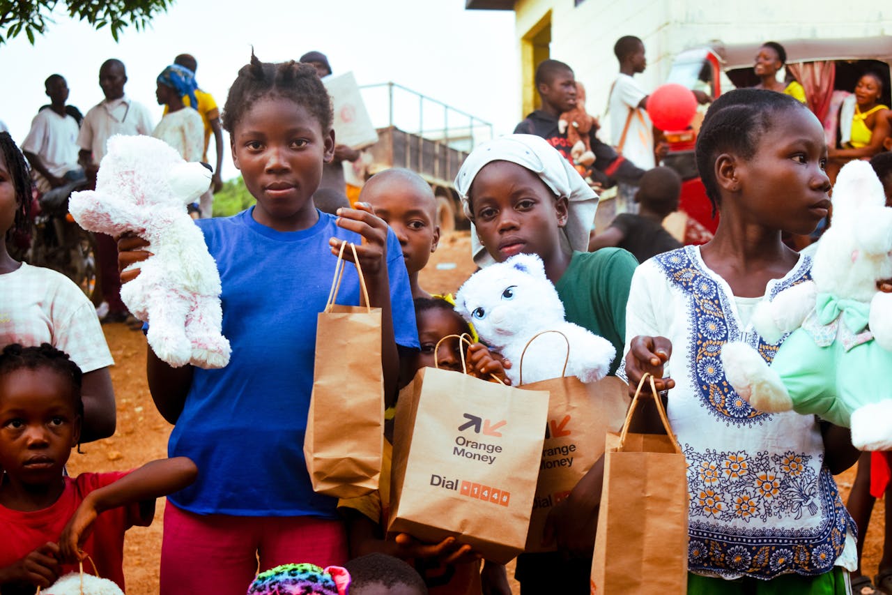 Children in Monrovia, Liberia hold stuffed toys and gift bags during a community event.